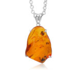 Pendentif en ambre avec un montant en argent sur fond blanc.