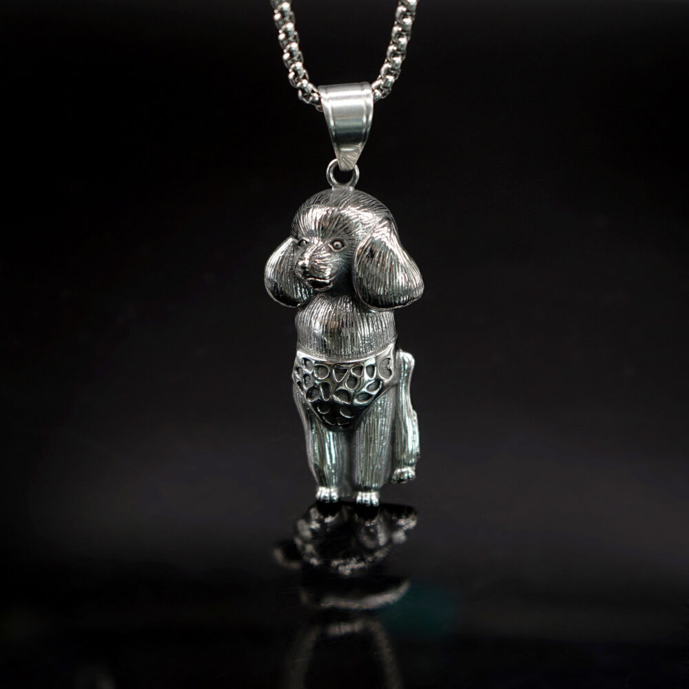 Pendentif représentant un caniche gris sur un fond noir.