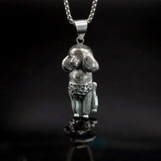 Pendentif représentant un caniche gris sur un fond noir.