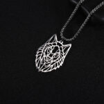 On voit un pendentif en forme de loup, argenté, sur fond noir.