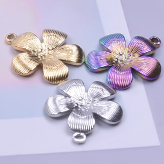 3 pendentifs en forme de fleur de sakura, un doré, un argenté, un violet holographique, sur support violet