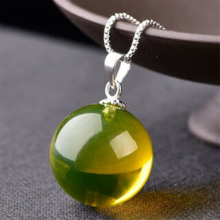 Pendentif en forme de boule en ambre sur fond gris.