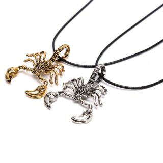 deux pendentifs en forme de scorpion, un doré un argenté, relié à des collier en tissu, sur fond blanc