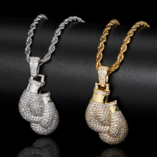 deux pendentifs avec chaine incluse en forme de paire de gants de boxe brillants avec strass, un argenté sur la gauche un doré sur la droite, sur fond noir