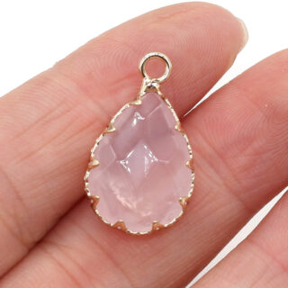 Pendentif quartz rose en forme de goutte d'eau tenu par une main.
