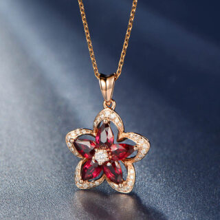 Pendentif doré en forme de fleur avec cinq pierres en rubis à l'intérieur.