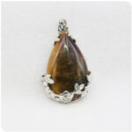 Photo d'un pendentif en pierre oeil de tigre sur un socle en argent plaqué à fleurs