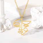 On voit un collier doré avec un pendentif doré qui représente le visage d'une femme.