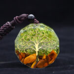 Photo d'unc ollier pendentif orgonite en olivine verte motif arbre de vie sur fond noir