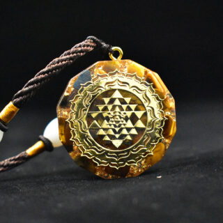 Photo d'un collier pendentif orgonite en œil de tigre motif Yantra sur fond noir