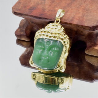 Pendentif en forme de tête de bouddha vert et doré sur fond bois et argent.