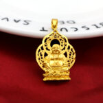 Pendentif doré représentant un bouddha, fond rouge et blanc.