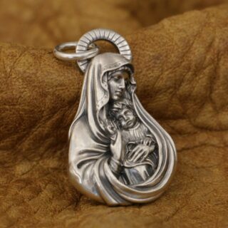 Pendentif de la vierge marie avec l'enfant jesus dans ses bras, posé sur un tissu marron en cuir