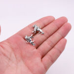 Dans le creux d'une main, on voit deux pendentifs argentés représentant des lionnes.