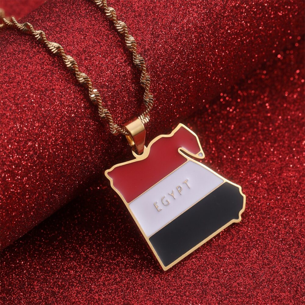 Pendentif en forme de pays de l'Egypte avec les couleurs du drapeau, posé sur un tissu rouge brillant