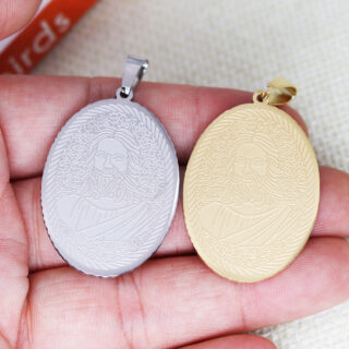 Pendentifs doré et argenté avec le portrait de Jésus tenus par une main.