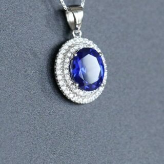 Photo représentant un pendentif en saphir posé sur un fond gris.