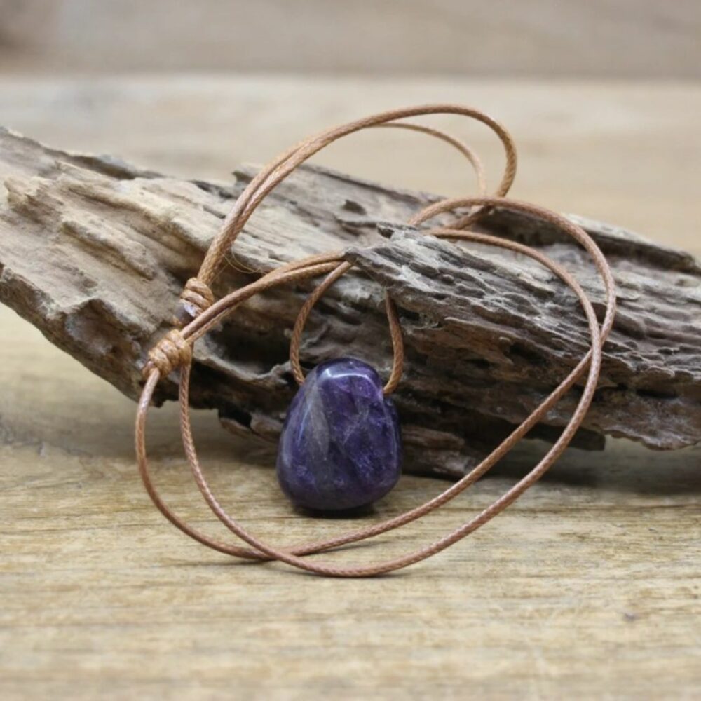 Pendentif pierre naturelle discret sur fond beige avec du bois