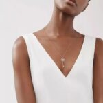 Pendentif clé luxueux et classe porté par une femme avec un haut blanc sur fond gris