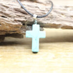 Pendentif croix en pierre naturelle sur fond beige