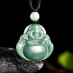 Pendentif religieux Bouddha rieur sculpté dans du jade vert, accroché par un cordon noir, sur un fond noir.