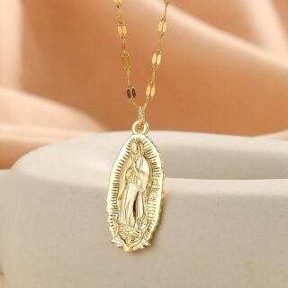 Pendentif religieux médaillon Vierge Marie suspendu par sa chaine dorée et mis en valeur sur un présentoir beige.