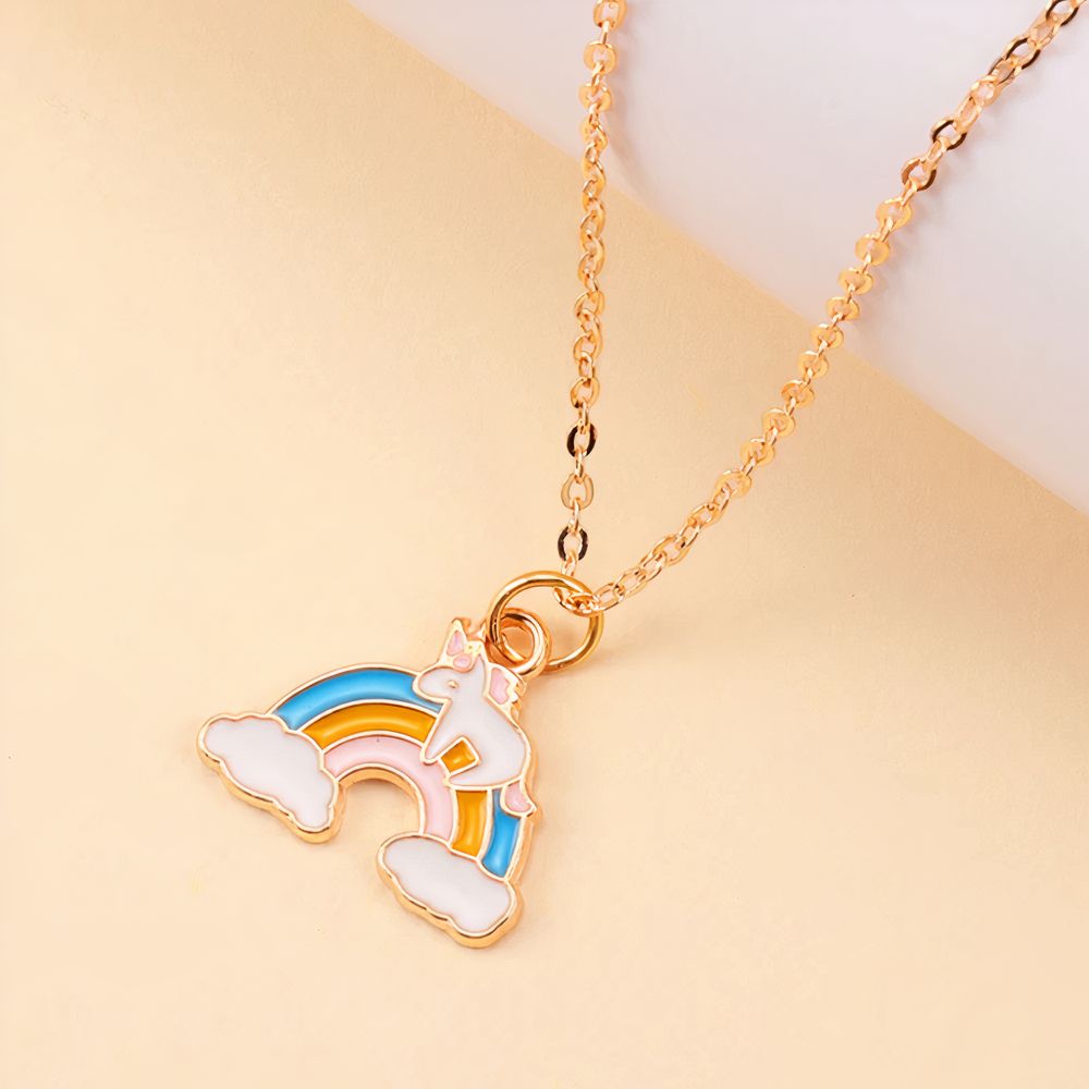 Pendentif doré enfant représentant une licorne sur un arc-en-ciel coloré, sur fond clair