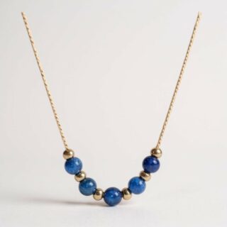 collier fin doré avec perles rondes en lapis lazuli bleu marine, sur fond neutre.